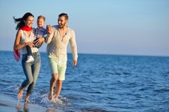 Η ευτυχής νέα οικογένεια έχει τη διασκέδαση στην παραλία που οργανώνεται και το άλμα στο ηλιοβασίλεμα Στοκ φωτογραφία με δικαίωμα ελεύθερης χρήσης Η ευτυχής νέα οικογένεια έχει τη διασκέδαση στην παραλία που οργανώνεται και το άλμα στο ηλιοβασίλεμα Στοκ φωτογραφία με δικαίωμα ελεύθερης χρήσης
