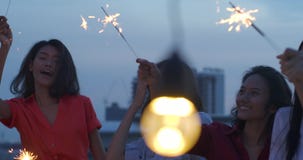 Η ευτυχής ομάδα νέων φίλων απολαμβάνει και παίζει sparkler στο τοπ κόμμα στεγών στο ηλιοβασίλεμα βραδιού Εορτασμός διακοπών εορτα φιλμ μικρού μήκους Η ευτυχής ομάδα νέων φίλων απολαμβάνει και παίζει sparkler στο τοπ κόμμα στεγών στο ηλιοβασίλεμα βραδιού Εορτασμός διακοπών εορτα φιλμ μικρού μήκους