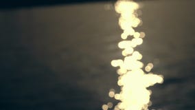Η κινηματογράφηση σε πρώτο πλάνο, θολωμένη εστίαση, στο φως του ήλιου ηλιοβασιλέματος απεικονίζεται στο νερό φιλμ μικρού μήκους Η κινηματογράφηση σε πρώτο πλάνο, θολωμένη εστίαση, στο φως του ήλιου ηλιοβασιλέματος απεικονίζεται στο νερό φιλμ μικρού μήκους
