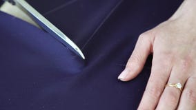 Η κινηματογράφηση σε πρώτο πλάνο των νέων χεριών γυναικών έκοψε το μπλε ύφασμα με το ψαλίδι σύμφωνα με το σχέδιο φιλμ μικρού μήκους Η κινηματογράφηση σε πρώτο πλάνο των νέων χεριών γυναικών έκοψε το μπλε ύφασμα με το ψαλίδι σύμφωνα με το σχέδιο φιλμ μικρού μήκους