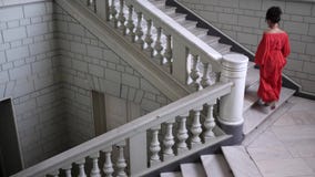 Η κομψή ηθοποιός στο κόκκινο φόρεμα στα υψηλά τακούνια αναρριχείται σε μια μεγάλη σκάλα στην όμορφη αίθουσα απόθεμα βίντεο Η κομψή ηθοποιός στο κόκκινο φόρεμα στα υψηλά τακούνια αναρριχείται σε μια μεγάλη σκάλα στην όμορφη αίθουσα απόθεμα βίντεο