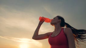 Η λεπτή όμορφη γυναίκα τρέχει στο καθαρό αέρα και πίνει από ένα μπουκάλι απόθεμα βίντεο Η λεπτή όμορφη γυναίκα τρέχει στο καθαρό αέρα και πίνει από ένα μπουκάλι απόθεμα βίντεο