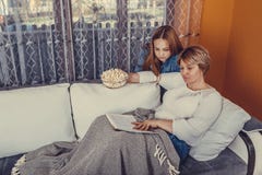 Η μητέρα και το έφηβη κόρη της διαβάζουν το βιβλίο και τρώνε popcorn στοκ φωτογραφίες Η μητέρα και το έφηβη κόρη της διαβάζουν το βιβλίο και τρώνε popcorn στοκ φωτογραφίες