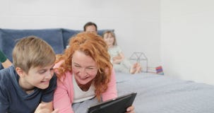Η μητέρα με το γέλιο γιων που προσέχει το αστείο βίντεο στον ψηφιακό υπολογιστή ταμπλετών που βρίσκεται στο κρεβάτι, ευτυχής οικο απόθεμα βίντεο Η μητέρα με το γέλιο γιων που προσέχει το αστείο βίντεο στον ψηφιακό υπολογιστή ταμπλετών που βρίσκεται στο κρεβάτι, ευτυχής οικο απόθεμα βίντεο