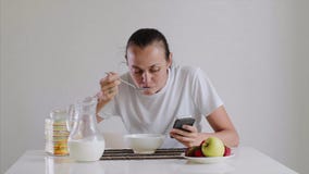 Η νέα γυναίκα έχει ένα πρόγευμα και κοιτάζει στο smartphone απόθεμα βίντεο Η νέα γυναίκα έχει ένα πρόγευμα και κοιτάζει στο smartphone απόθεμα βίντεο