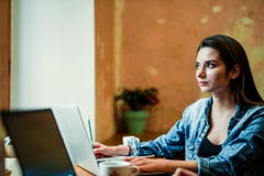 Η νέα γυναίκα σπουδαστής κάθεται κοντά στο παράθυρο με το lap-top και κοιτάζει μέσω του παραθύρου στοκ εικόνες με δικαίωμα ελεύθερης χρήσης Η νέα γυναίκα σπουδαστής κάθεται κοντά στο παράθυρο με το lap-top και κοιτάζει μέσω του παραθύρου στοκ εικόνες με δικαίωμα ελεύθερης χρήσης