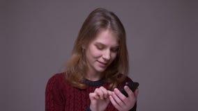 Η νέα εργασία γυναικών σπουδαστών με το smartphone γυρίζει στη κάμερα και χαμογελά στο γκρίζο υπόβαθρο απόθεμα βίντεο Η νέα εργασία γυναικών σπουδαστών με το smartphone γυρίζει στη κάμερα και χαμογελά στο γκρίζο υπόβαθρο απόθεμα βίντεο