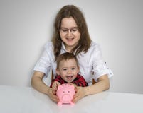Η νέα μητέρα γνωρίζει το παιδί της συλλέγει τα νομίσματα στο piggy BA χρημάτων στοκ εικόνες Η νέα μητέρα γνωρίζει το παιδί της συλλέγει τα νομίσματα στο piggy BA χρημάτων στοκ εικόνες