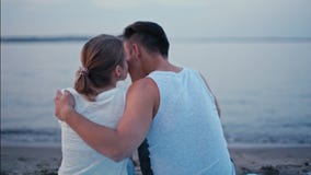 Η νέα οικογένεια κάθεται και αγκαλιάζει στην ακτή λιμνών το θερινό βράδυ απόθεμα βίντεο Η νέα οικογένεια κάθεται και αγκαλιάζει στην ακτή λιμνών το θερινό βράδυ απόθεμα βίντεο