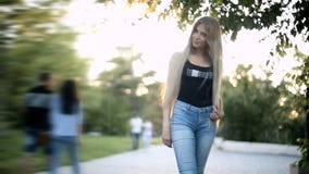 Η νέα προκλητική ξανθή γυναίκα που η μακριά ρέοντας τρίχα περπατά στο πάρκο backlight από τον ήλιο λάμπει Η νέα προκλητική ξανθή γυναίκα που η μακριά ρέοντας τρίχα περπατά στο πάρκο backlight από τον ήλιο λάμπει