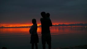 Η οικογένεια εξετάζει την απόσταση στο ηλιοβασίλεμα καθώς ο ήλιος πηγαίνει κάτω φιλμ μικρού μήκους Η οικογένεια εξετάζει την απόσταση στο ηλιοβασίλεμα καθώς ο ήλιος πηγαίνει κάτω φιλμ μικρού μήκους