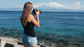 Η πλάγια όψη του φωτογράφου τουριστών κοριτσιών παίρνει τις εικόνες του ωκεανού και των βουνών φιλμ μικρού μήκους Η πλάγια όψη του φωτογράφου τουριστών κοριτσιών παίρνει τις εικόνες του ωκεανού και των βουνών φιλμ μικρού μήκους