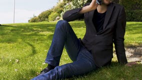 Η συνεδρίαση επιχειρησιακών προσώπων στο χορτοτάπητα στο πάρκο και η ομιλία στο smartphone, αστικό χαλαρώνουν απόθεμα βίντεο Η συνεδρίαση επιχειρησιακών προσώπων στο χορτοτάπητα στο πάρκο και η ομιλία στο smartphone, αστικό χαλαρώνουν απόθεμα βίντεο