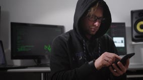 Η υπόγεια οργάνωση Το lap-top στα όργανα ελέγχου άρχισε τη διαδικασία Ένας χάκερ με ένα smartphone σε ετοιμότητα κάθεται Η υπόγεια οργάνωση Το lap-top στα όργανα ελέγχου άρχισε τη διαδικασία Ένας χάκερ με ένα smartphone σε ετοιμότητα κάθεται