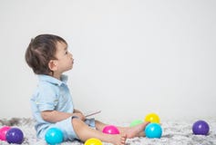 Η χαριτωμένη ασιατική συνεδρίαση παιδιών κινηματογραφήσεων σε πρώτο πλάνο και εξετάζει το διάστημα στο άσπρο κατασκευασμένο υπόβα Στοκ Εικόνες Η χαριτωμένη ασιατική συνεδρίαση παιδιών κινηματογραφήσεων σε πρώτο πλάνο και εξετάζει το διάστημα στο άσπρο κατασκευασμένο υπόβα Στοκ Εικόνες