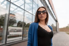 Η όμορφη αρκετά προκλητική νέα γυναίκα hipster στα μοντέρνα γυαλιά ηλίου σε ένα πλεκτό ακρωτήριο σε μια μπλούζα με τη δαντέλλα στ στοκ εικόνες Η όμορφη αρκετά προκλητική νέα γυναίκα hipster στα μοντέρνα γυαλιά ηλίου σε ένα πλεκτό ακρωτήριο σε μια μπλούζα με τη δαντέλλα στ στοκ εικόνες