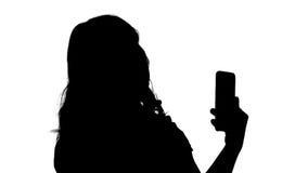 Η όμορφη γυναίκα σκιαγραφιών η χρησιμοποίηση του τηλεφώνου της όπως έναν καθρέφτη Η όμορφη γυναίκα σκιαγραφιών η χρησιμοποίηση του τηλεφώνου της όπως έναν καθρέφτη