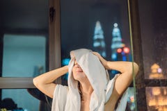Η όμορφη γυναίκα σκουπίζει την τρίχα της μετά από ένα ντους στο υπόβαθρο ενός παραθύρου με μια πανοραμική άποψη της πόλης νύχτας στοκ εικόνες Η όμορφη γυναίκα σκουπίζει την τρίχα της μετά από ένα ντους στο υπόβαθρο ενός παραθύρου με μια πανοραμική άποψη της πόλης νύχτας στοκ εικόνες