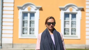 Η όμορφη γυναίκα στέκεται στο υπόβαθρο των παραθύρων ενός όμορφου σπιτιού και των χαμόγελων, εξετάζοντας τη κάμερα φιλμ μικρού μήκους Η όμορφη γυναίκα στέκεται στο υπόβαθρο των παραθύρων ενός όμορφου σπιτιού και των χαμόγελων, εξετάζοντας τη κάμερα φιλμ μικρού μήκους