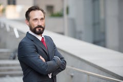 Θετικός επιχειρηματίας που κοιτάζει μακριά με τα όπλα που διασχίζονται στοκ φωτογραφία με δικαίωμα ελεύθερης χρήσης Θετικός επιχειρηματίας που κοιτάζει μακριά με τα όπλα που διασχίζονται στοκ φωτογραφία με δικαίωμα ελεύθερης χρήσης