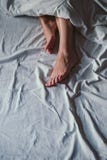 Θηλυκά πόδια λοξά στο κρεβάτι στοκ φωτογραφία με δικαίωμα ελεύθερης χρήσης Θηλυκά πόδια λοξά στο κρεβάτι στοκ φωτογραφία με δικαίωμα ελεύθερης χρήσης