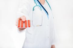 Θηλυκό πακέτο εκμετάλλευσης χεριών γιατρών των κόκκινων χαπιών, εστίαση στα χάπια στοκ εικόνα Θηλυκό πακέτο εκμετάλλευσης χεριών γιατρών των κόκκινων χαπιών, εστίαση στα χάπια στοκ εικόνα