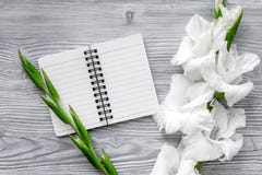 Θηλυκός χώρος εργασίας γραφείων Σημειωματάριο και gladiolus στην γκρίζα ξύλινη τοπ άποψη υποβάθρου στοκ φωτογραφία με δικαίωμα ελεύθερης χρήσης Θηλυκός χώρος εργασίας γραφείων Σημειωματάριο και gladiolus στην γκρίζα ξύλινη τοπ άποψη υποβάθρου στοκ φωτογραφία με δικαίωμα ελεύθερης χρήσης