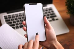 Θηλυκά χέρια που κρατούν ένα άσπρο τηλέφωνο με την απομονωμένη οθόνη σε έναν πίνακα με το lap-top στοκ φωτογραφίες με δικαίωμα ελεύθερης χρήσης Θηλυκά χέρια που κρατούν ένα άσπρο τηλέφωνο με την απομονωμένη οθόνη σε έναν πίνακα με το lap-top στοκ φωτογραφίες με δικαίωμα ελεύθερης χρήσης