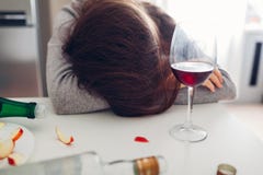 Θηλυκός εθισμός οινοπνεύματος Νέος ύπνος γυναικών στον πίνακα κουζινών που περιβάλλεται με τα μπουκάλια κρασιού στοκ εικόνες με δικαίωμα ελεύθερης χρήσης Θηλυκός εθισμός οινοπνεύματος Νέος ύπνος γυναικών στον πίνακα κουζινών που περιβάλλεται με τα μπουκάλια κρασιού στοκ εικόνες με δικαίωμα ελεύθερης χρήσης