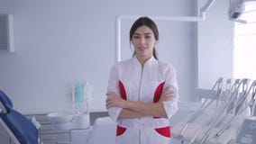 Θηλυκός οδοντίατρος που στέκεται και που χαμογελά στη κάμερα τα όπλα που διασχίζονται με απόθεμα βίντεο Θηλυκός οδοντίατρος που στέκεται και που χαμογελά στη κάμερα τα όπλα που διασχίζονται με απόθεμα βίντεο