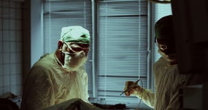 Ιατρική ομάδα που εκτελεί τη λειτουργία στο λειτουργούν δωμάτιο νοσοκομείων φιλμ μικρού μήκους Ιατρική ομάδα που εκτελεί τη λειτουργία στο λειτουργούν δωμάτιο νοσοκομείων φιλμ μικρού μήκους