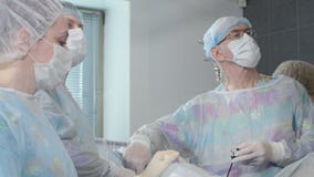 Ιατρική ομάδα που εκτελεί τη χειρουργική λειτουργία στο φωτεινό σύγχρονο λειτουργούν δωμάτιο φιλμ μικρού μήκους Ιατρική ομάδα που εκτελεί τη χειρουργική λειτουργία στο φωτεινό σύγχρονο λειτουργούν δωμάτιο φιλμ μικρού μήκους
