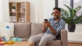 Ινδικό άτομο που χρησιμοποιεί το smartphone μετά από να καθαρίσει το σπίτι απόθεμα βίντεο Ινδικό άτομο που χρησιμοποιεί το smartphone μετά από να καθαρίσει το σπίτι απόθεμα βίντεο