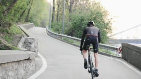 Ισχυρός επαγγελματικός ποδηλάτης με τους μεμβρανοειδείς ισχυρούς μυς ποδιών που οδηγούν τον ανήφορο από τη σέλα Η πλάτη ακολουθεί απόθεμα βίντεο Ισχυρός επαγγελματικός ποδηλάτης με τους μεμβρανοειδείς ισχυρούς μυς ποδιών που οδηγούν τον ανήφορο από τη σέλα Η πλάτη ακολουθεί απόθεμα βίντεο
