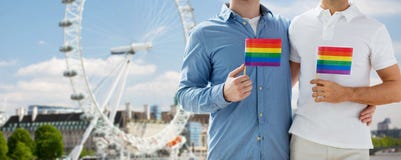 Κλείστε επάνω του αρσενικού ομοφυλοφιλικού ζεύγους με τις σημαίες ουράνιων τόξων στοκ εικόνα Κλείστε επάνω του αρσενικού ομοφυλοφιλικού ζεύγους με τις σημαίες ουράνιων τόξων στοκ εικόνα