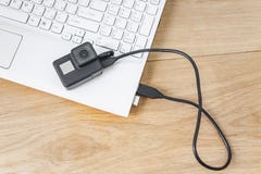 Κάμερα δράσης που συνδέεται με ένα άσπρο lap-top, στα πλαίσια ενός ξύλινου πίνακα στοκ εικόνες Κάμερα δράσης που συνδέεται με ένα άσπρο lap-top, στα πλαίσια ενός ξύλινου πίνακα στοκ εικόνες