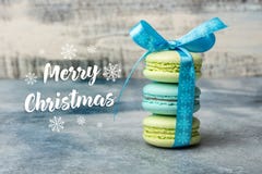 Κάρτα Χαρούμενα Χριστούγεννας τρία macarons δένονται από μια μπλε κορδέλλα στοκ φωτογραφίες Κάρτα Χαρούμενα Χριστούγεννας τρία macarons δένονται από μια μπλε κορδέλλα στοκ φωτογραφίες