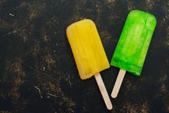 Κίτρινα και πράσινα popsicles σε ένα σκοτεινό αγροτικό υπόβαθρο Τοπ άποψη, διάστημα στοκ εικόνες Κίτρινα και πράσινα popsicles σε ένα σκοτεινό αγροτικό υπόβαθρο Τοπ άποψη, διάστημα στοκ εικόνες