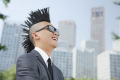 Καλά-ντυμένος νεαρός άνδρας με Mohawk και γυαλιά ηλίου που χαμογελούν, ουρανοξύστες στο υπόβαθρο στοκ εικόνες με δικαίωμα ελεύθερης χρήσης Καλά-ντυμένος νεαρός άνδρας με Mohawk και γυαλιά ηλίου που χαμογελούν, ουρανοξύστες στο υπόβαθρο στοκ εικόνες με δικαίωμα ελεύθερης χρήσης