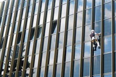 Καθαριστής παραθύρων ορειβατών που καθαρίζει τον εξωτερικό τοίχο γυαλιού ενός κτηρίου στοκ φωτογραφία Καθαριστής παραθύρων ορειβατών που καθαρίζει τον εξωτερικό τοίχο γυαλιού ενός κτηρίου στοκ φωτογραφία