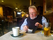 Καλά ντυμένο ανώτερο άτομο σε resturant από το φραγμό που βάζει την υπογεγραμμένη απόδειξη πιστωτικών καρτών πίσω στο φάκελλο με στοκ φωτογραφία Καλά ντυμένο ανώτερο άτομο σε resturant από το φραγμό που βάζει την υπογεγραμμένη απόδειξη πιστωτικών καρτών πίσω στο φάκελλο με στοκ φωτογραφία