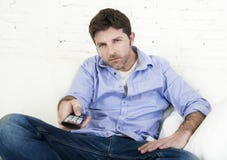 Καναπές τηλεοπτικών στο σπίτι καθιστικών προσοχής ατόμων με τον τηλεχειρισμό που φαίνεται πολύ ενδιαφερόμενο Στοκ Εικόνες Καναπές τηλεοπτικών στο σπίτι καθιστικών προσοχής ατόμων με τον τηλεχειρισμό που φαίνεται πολύ ενδιαφερόμενο Στοκ Εικόνες
