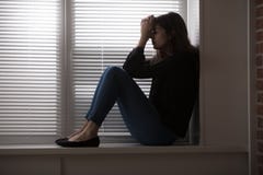 Καταθλιπτική συνεδρίαση γυναικών από το παράθυρο στοκ εικόνες Καταθλιπτική συνεδρίαση γυναικών από το παράθυρο στοκ εικόνες