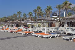 Κενά deckchairs με τα στρώματα και τις πετσέτες και ομπρέλες με το α στοκ φωτογραφία με δικαίωμα ελεύθερης χρήσης Κενά deckchairs με τα στρώματα και τις πετσέτες και ομπρέλες με το α στοκ φωτογραφία με δικαίωμα ελεύθερης χρήσης