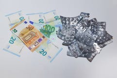 Κενές φουσκάλες από τα χάπια και ευρο- χρήματα σε ένα άσπρο υπόβαθρο Η έννοια του υψηλού κόστους των φαρμάκων στοκ εικόνα Κενές φουσκάλες από τα χάπια και ευρο- χρήματα σε ένα άσπρο υπόβαθρο Η έννοια του υψηλού κόστους των φαρμάκων στοκ εικόνα