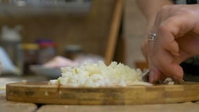 Κινηματογράφηση σε πρώτο πλάνο των μέσων ηλικίας τεμαχίζοντας κρεμμυδιών χεριών γυναικών στον τέμνοντα πίνακα φιλμ μικρού μήκους Κινηματογράφηση σε πρώτο πλάνο των μέσων ηλικίας τεμαχίζοντας κρεμμυδιών χεριών γυναικών στον τέμνοντα πίνακα φιλμ μικρού μήκους