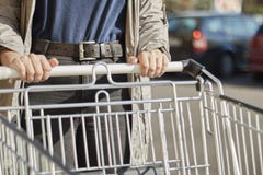 Κινηματογράφηση σε πρώτο πλάνο μπροστινής άποψης με μια εκλεκτική εστίαση ενός έφηβη που κινεί ένα κάρρο αγορών έξω από μια υπερα στοκ εικόνες με δικαίωμα ελεύθερης χρήσης Κινηματογράφηση σε πρώτο πλάνο μπροστινής άποψης με μια εκλεκτική εστίαση ενός έφηβη που κινεί ένα κάρρο αγορών έξω από μια υπερα στοκ εικόνες με δικαίωμα ελεύθερης χρήσης