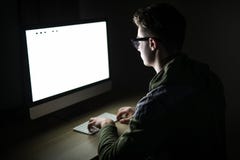 Κινηματογράφηση σε πρώτο πλάνο της συνεδρίασης και της χρησιμοποίησης νεαρών άνδρων του κενού υπολογιστή οθόνης στο σκοτεινό δωμά στοκ φωτογραφίες με δικαίωμα ελεύθερης χρήσης Κινηματογράφηση σε πρώτο πλάνο της συνεδρίασης και της χρησιμοποίησης νεαρών άνδρων του κενού υπολογιστή οθόνης στο σκοτεινό δωμά στοκ φωτογραφίες με δικαίωμα ελεύθερης χρήσης