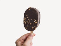 Κλείστε επάνω τη φωτογραφία του νόστιμου yummy εύγευστου ζαχαρούχου γλυκού με το παγωτό κάλυψης σοκολάτας στο χέρι της γυναίκας π στοκ εικόνες Κλείστε επάνω τη φωτογραφία του νόστιμου yummy εύγευστου ζαχαρούχου γλυκού με το παγωτό κάλυψης σοκολάτας στο χέρι της γυναίκας π στοκ εικόνες