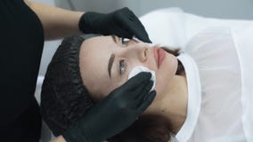 Κλείστε επάνω το beautician καθαρίζει το δέρμα του προσώπου γυναικών πριν από τη διαδικασία, σε αργή κίνηση φιλμ μικρού μήκους Κλείστε επάνω το beautician καθαρίζει το δέρμα του προσώπου γυναικών πριν από τη διαδικασία, σε αργή κίνηση φιλμ μικρού μήκους